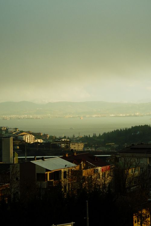 Free View of a town by a lake with fog and distant mountains during an evening. Stock Photo