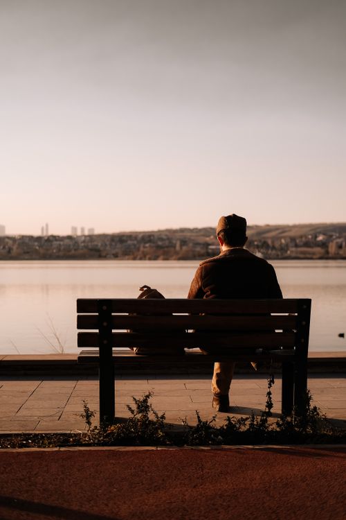 Free A serene scene of a man sitting on a bench by the lake in Ankara, Türkiye, during sunset. Stock Photo