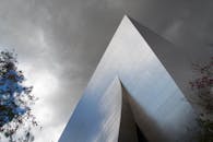 镜头捕捉了一座光滑的银色现代建筑，背景是多云天气，显得格外戏剧性