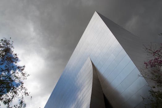 镜头捕捉了一座光滑的银色现代建筑，背景是多云天气，显得格外戏剧性