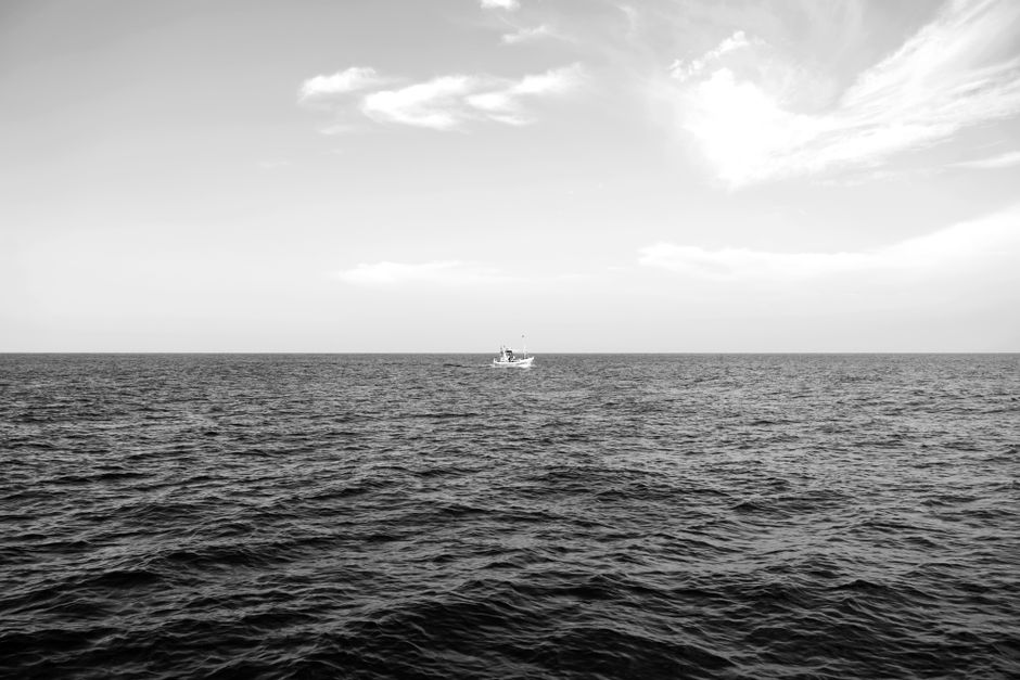 Monochrome image of a tranquil sea with a lone boat on the horizon near Galle, Sri Lanka.