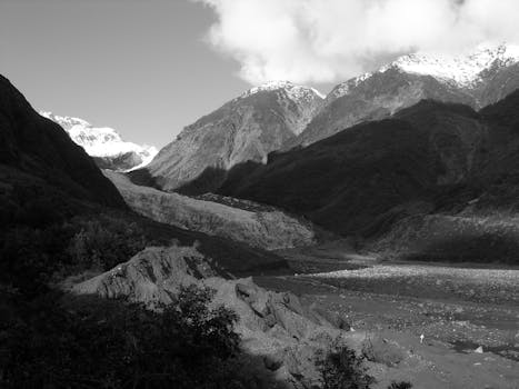 Black and white shot of a dramatic mountainous landscape with eroded terrain and cloud cover.
