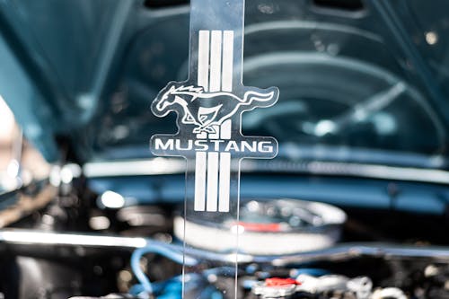 Close-up of Ford Mustang Sign on the Background of an Opened Car Hood 