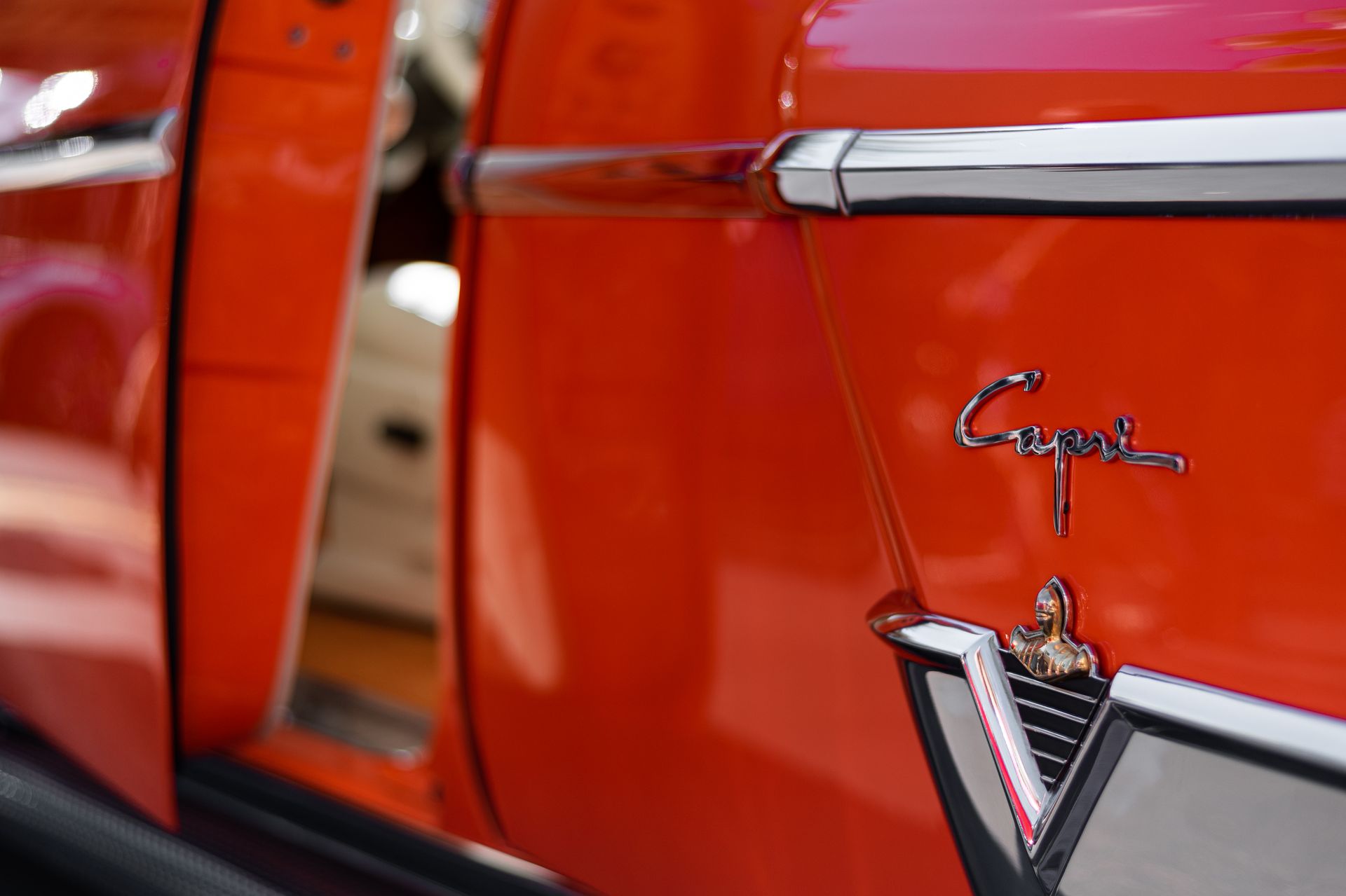 Detailed close-up of a vintage red Capri car emblem with an open door in Tampa, FL.