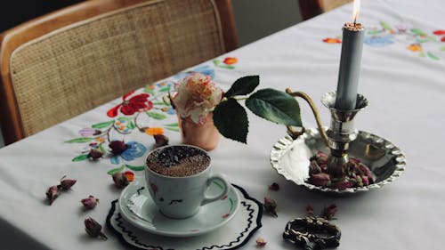 Photo of a Cup of Coffee with a Candle and a Flower
