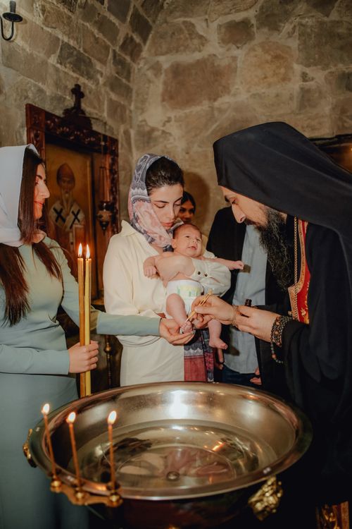 Free Intimate Orthodox baptism ceremony in a historic church setting, capturing religious tradition. Stock Photo