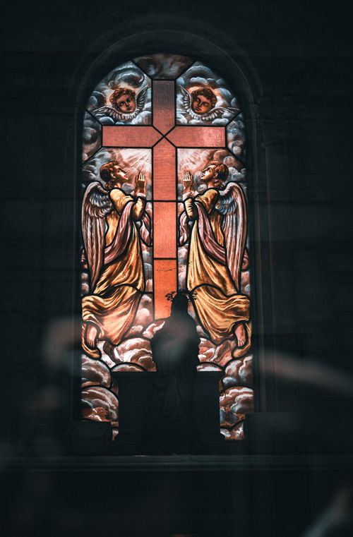 Free Majestic stained glass window featuring angels and cross in Gothic church interior. Stock Photo