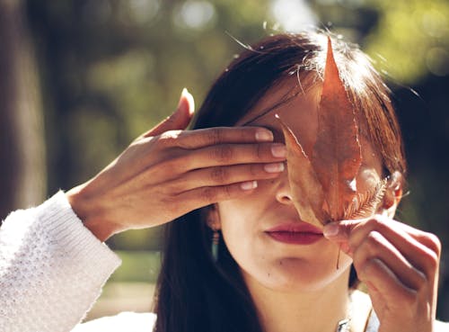 Woman Covering Face with Leaf and Hand