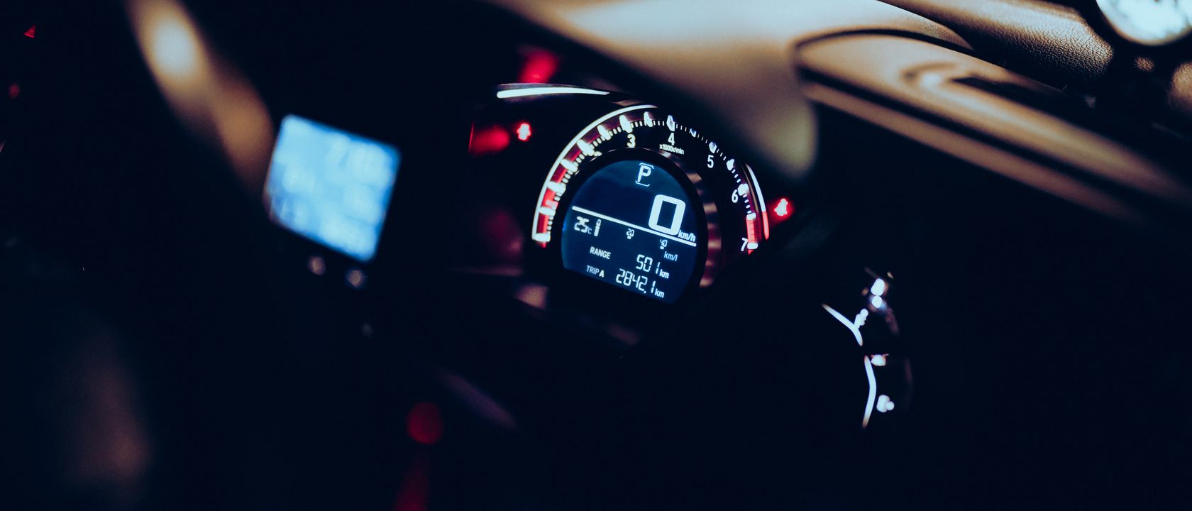 Close-up of a car dashboard at night with illuminated speedometer and tech displays.