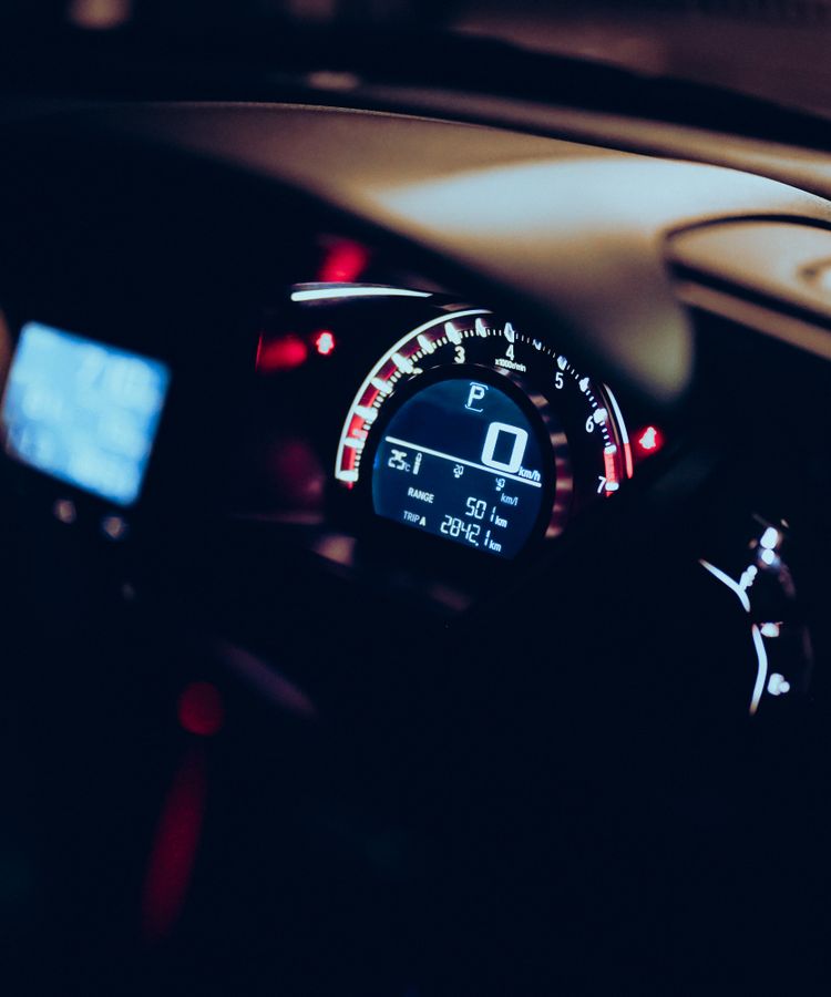 Close-up of a car dashboard at night with illuminated speedometer and tech displays.