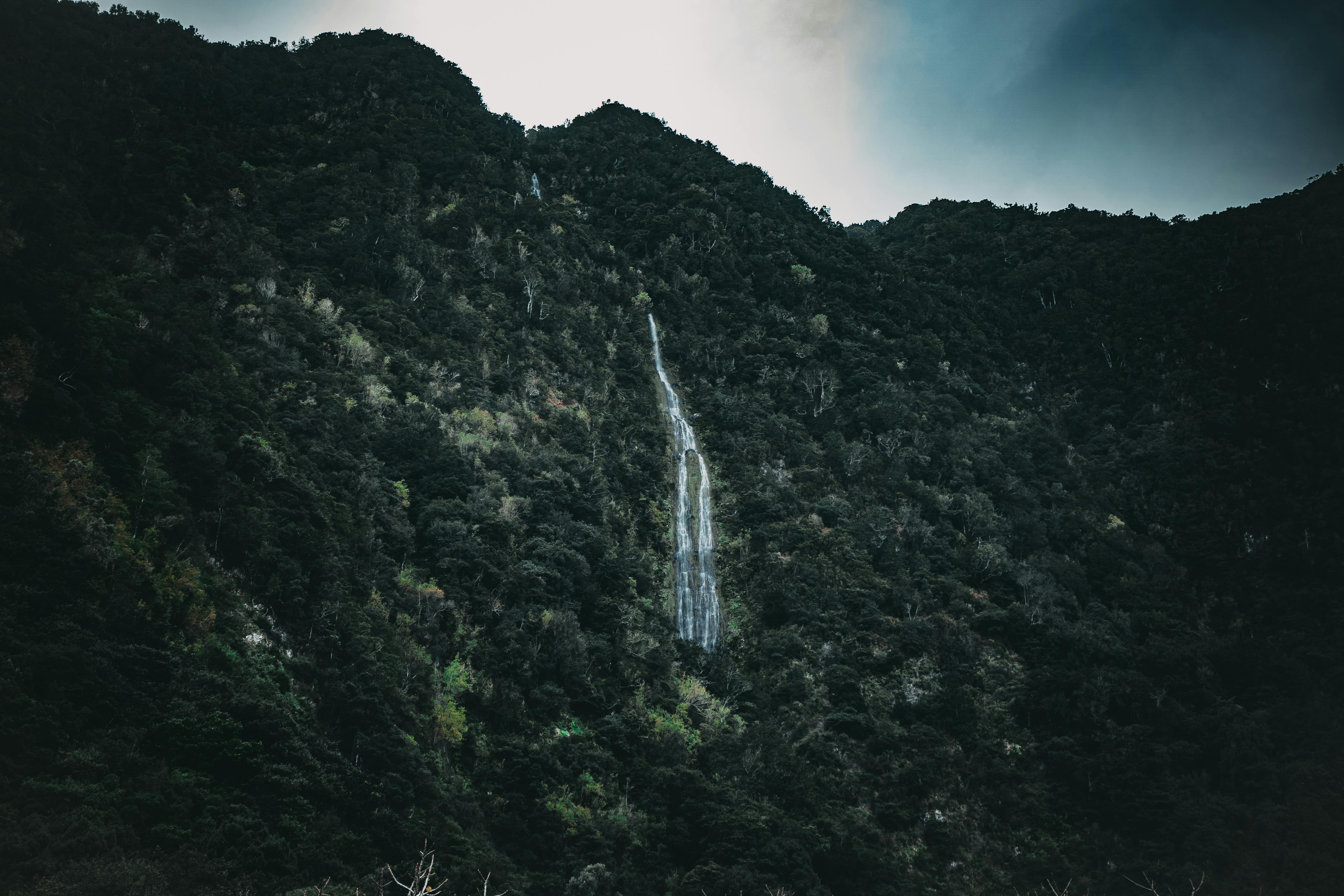 Stunning waterfall cascading down lush green mountains in Madeira, Portugal.
