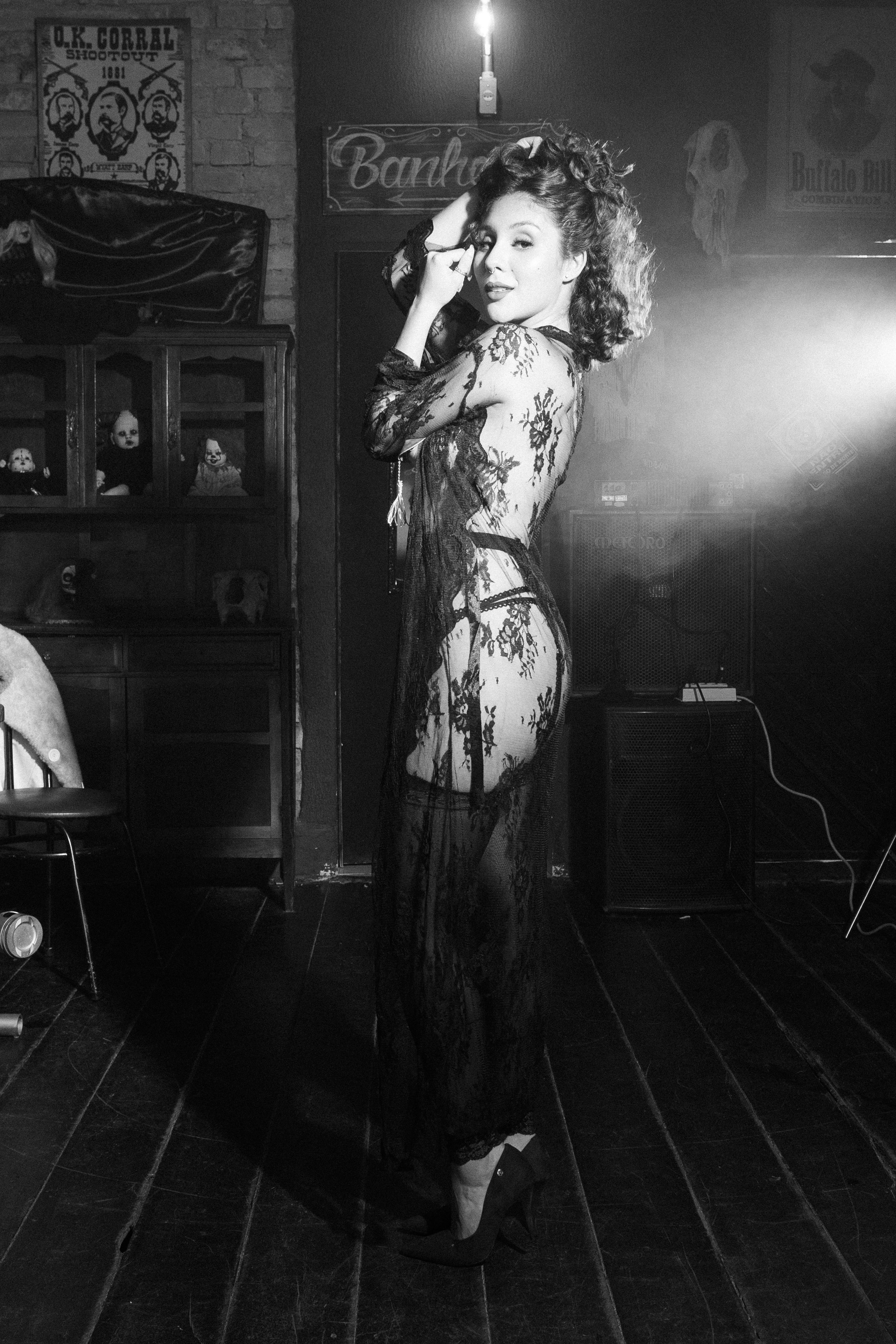 Free A striking portrait of a woman in a lace dress, posing gracefully in a vintage studio setting. Stock Photo