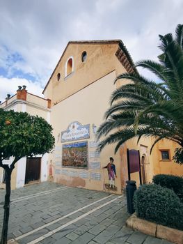 Historic colonial church exterior with a ceramic mural and palm tree.
