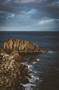 Stunning view of rocky formations along Madeira's coast with dramatic lighting under a cloudy sky.