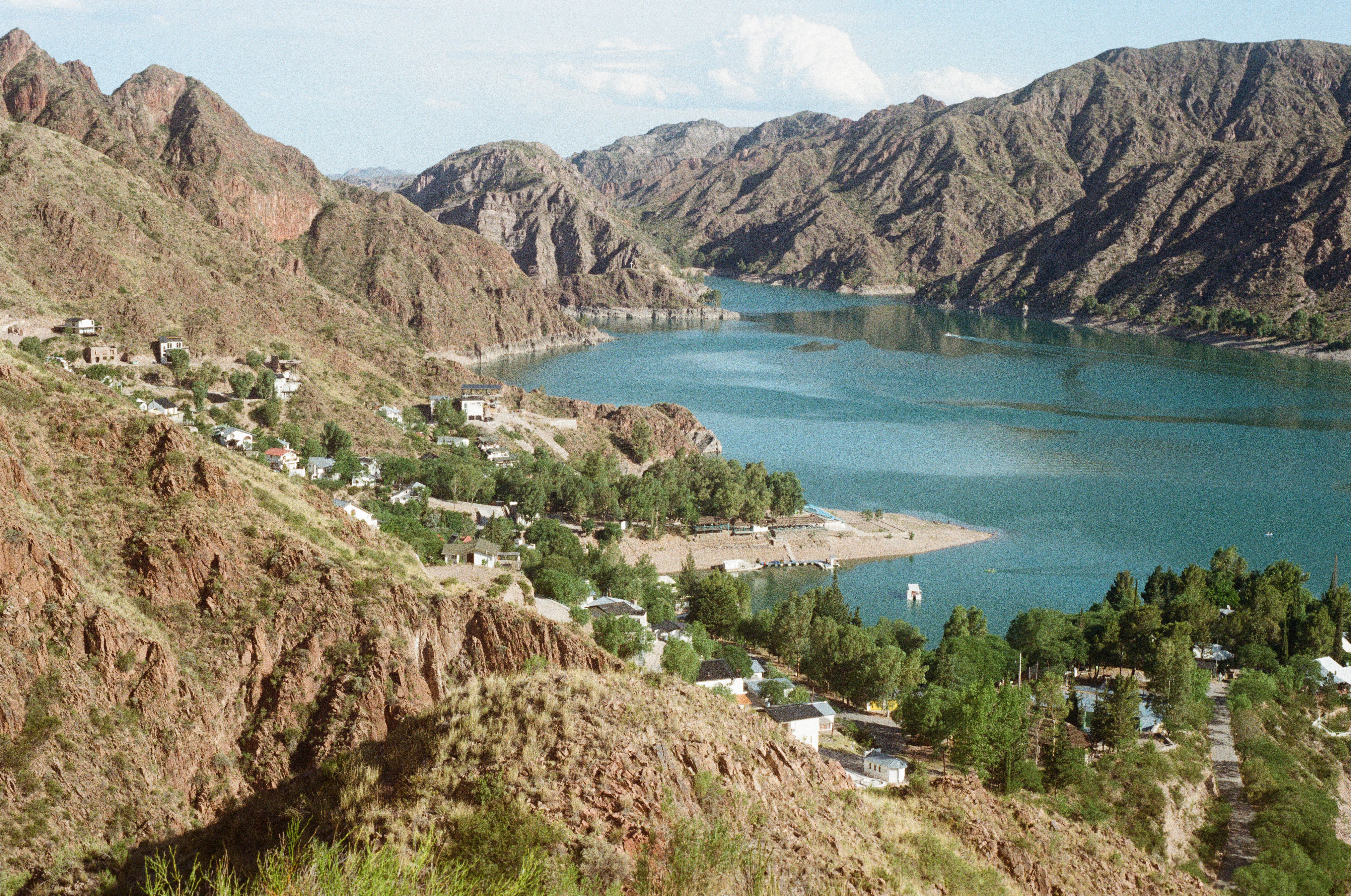 Breathtaking aerial view of a tranquil lakeside village surrounded by rugged mountains.