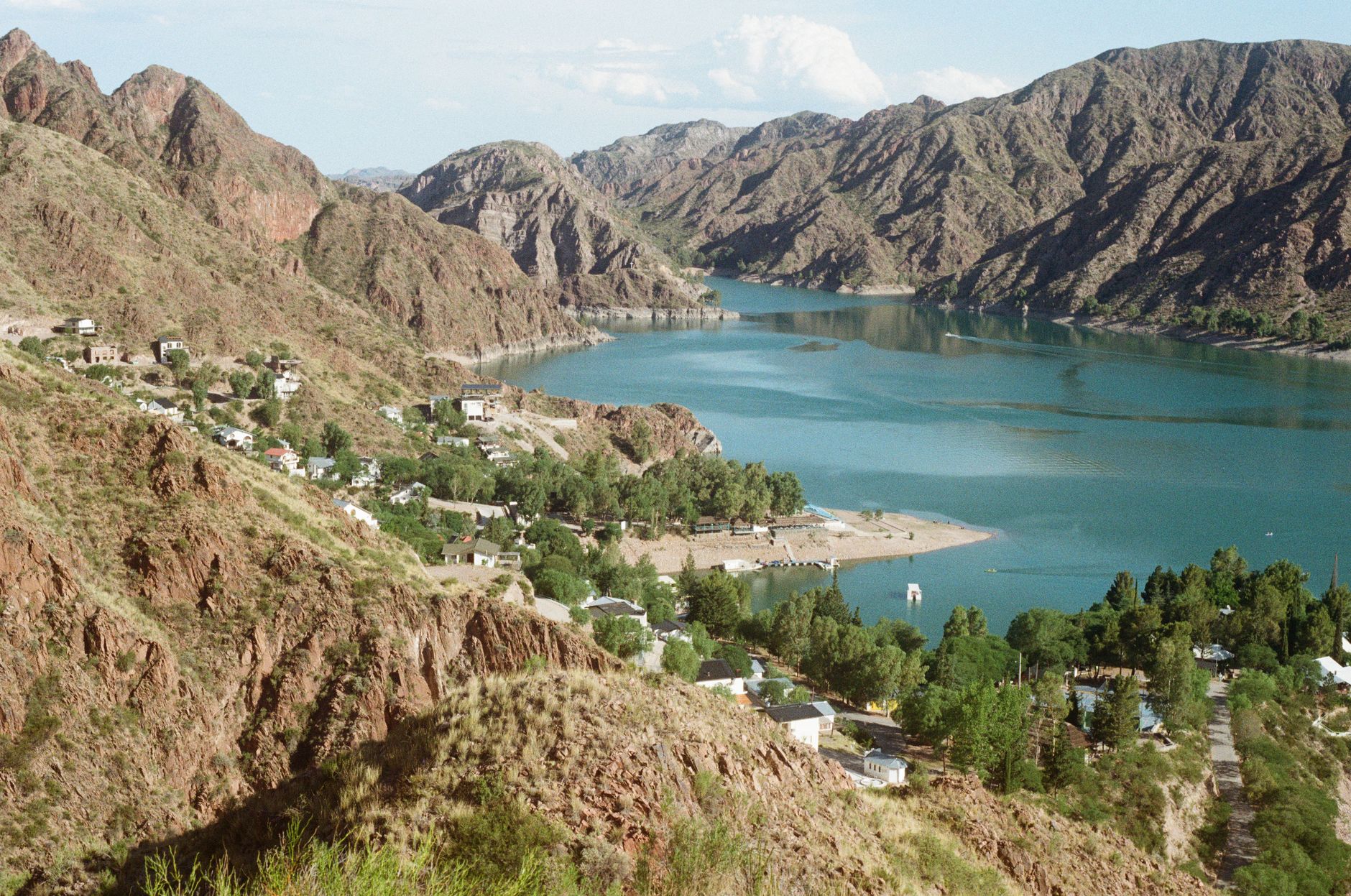 Breathtaking aerial view of a tranquil lakeside village surrounded by rugged mountains.