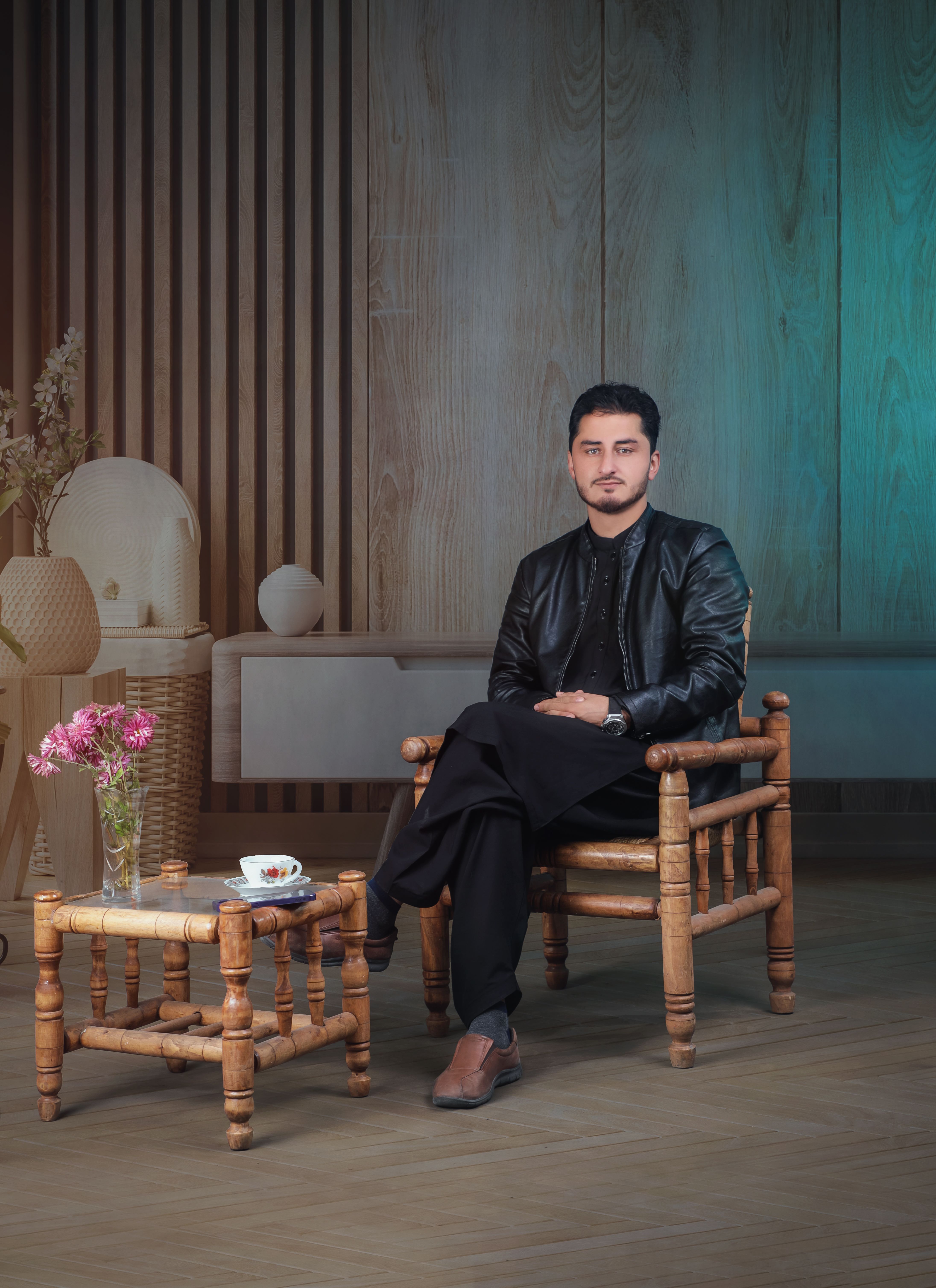 Stylish adult man in leather jacket sitting on a wooden chair indoors.