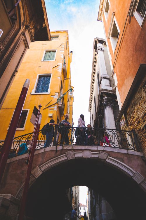 Free Venice street scene featuring a picturesque bridge with tourists and colorful buildings. Stock Photo