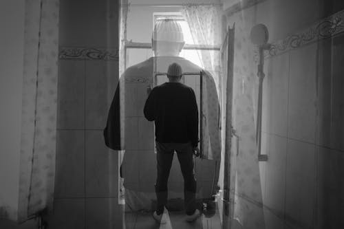 Double Exposure of Man Standing Alone in Bathroom