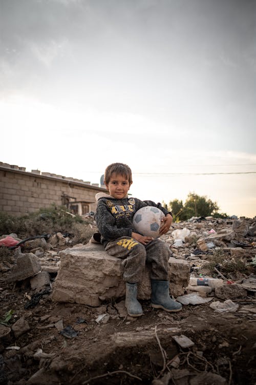 Boy Sitting with Ball in Ruins