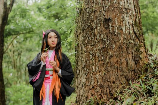 A young woman in a traditional kimono stands amidst a serene forest, capturing the essence of nature and cultural heritage.