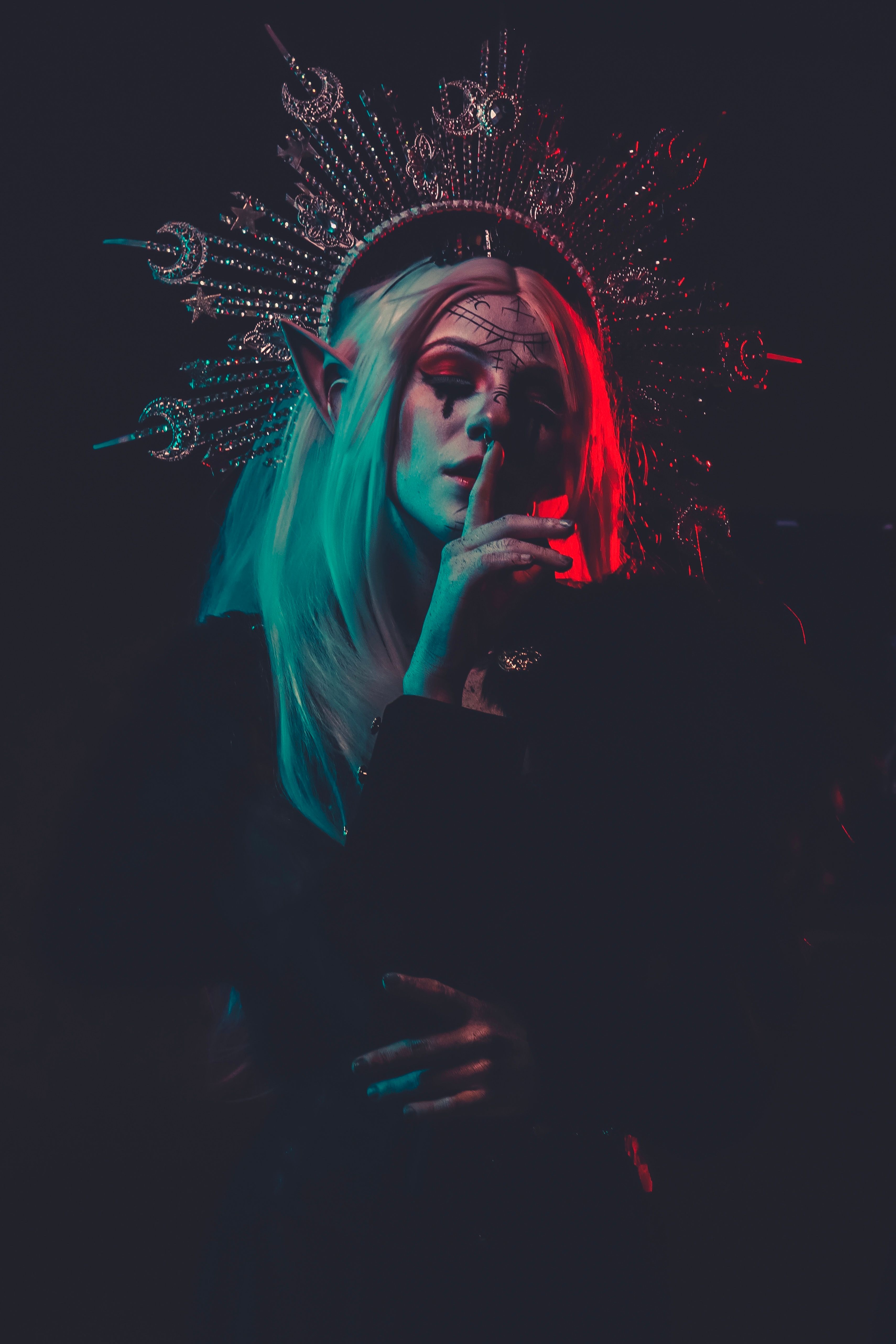 A captivating fantasy figure with crown and makeup in artistic split lighting, creating a mysterious allure.