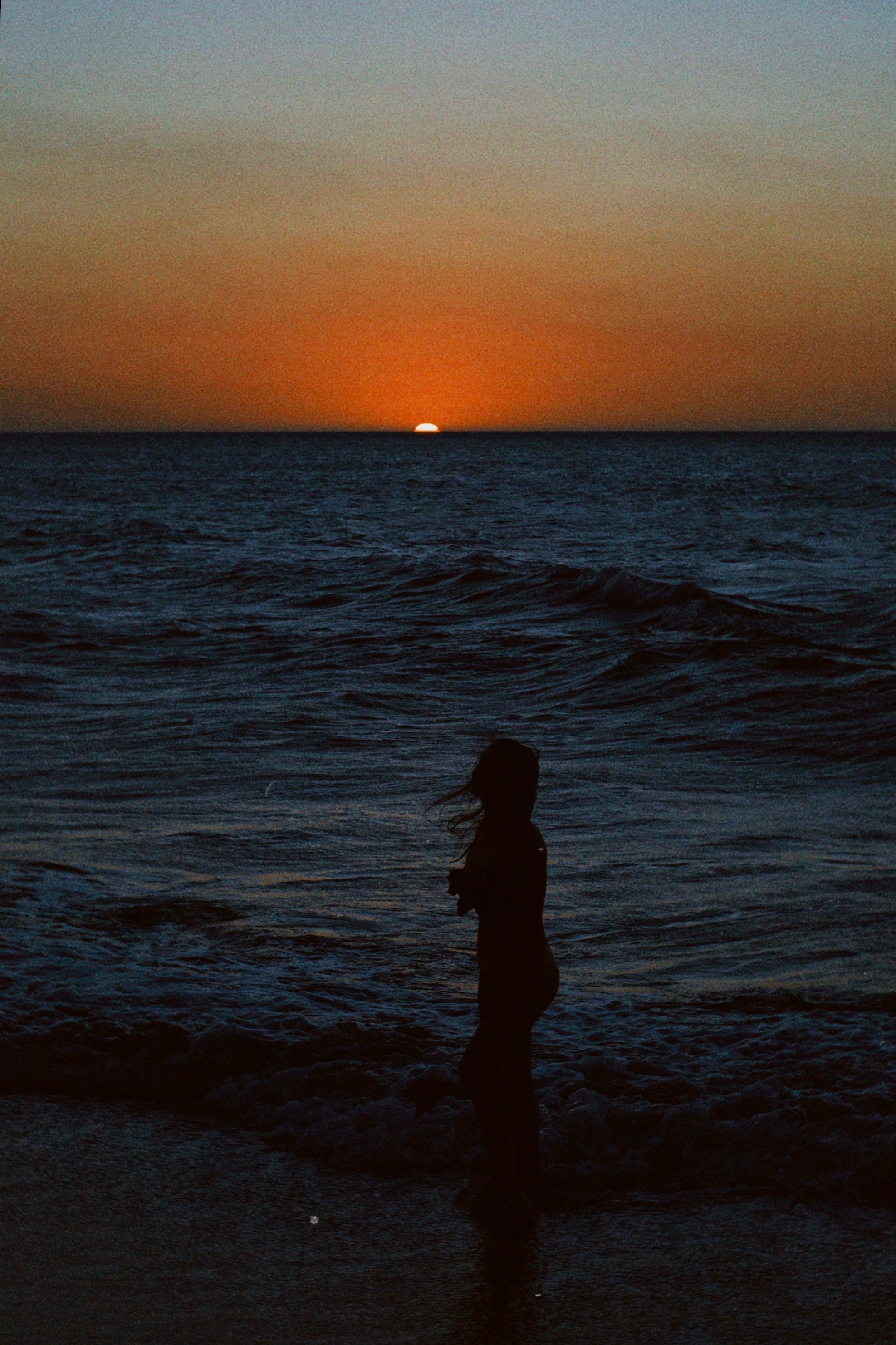 Silhouette of a Woman on the Beach at Sunset · Free Stock Photo