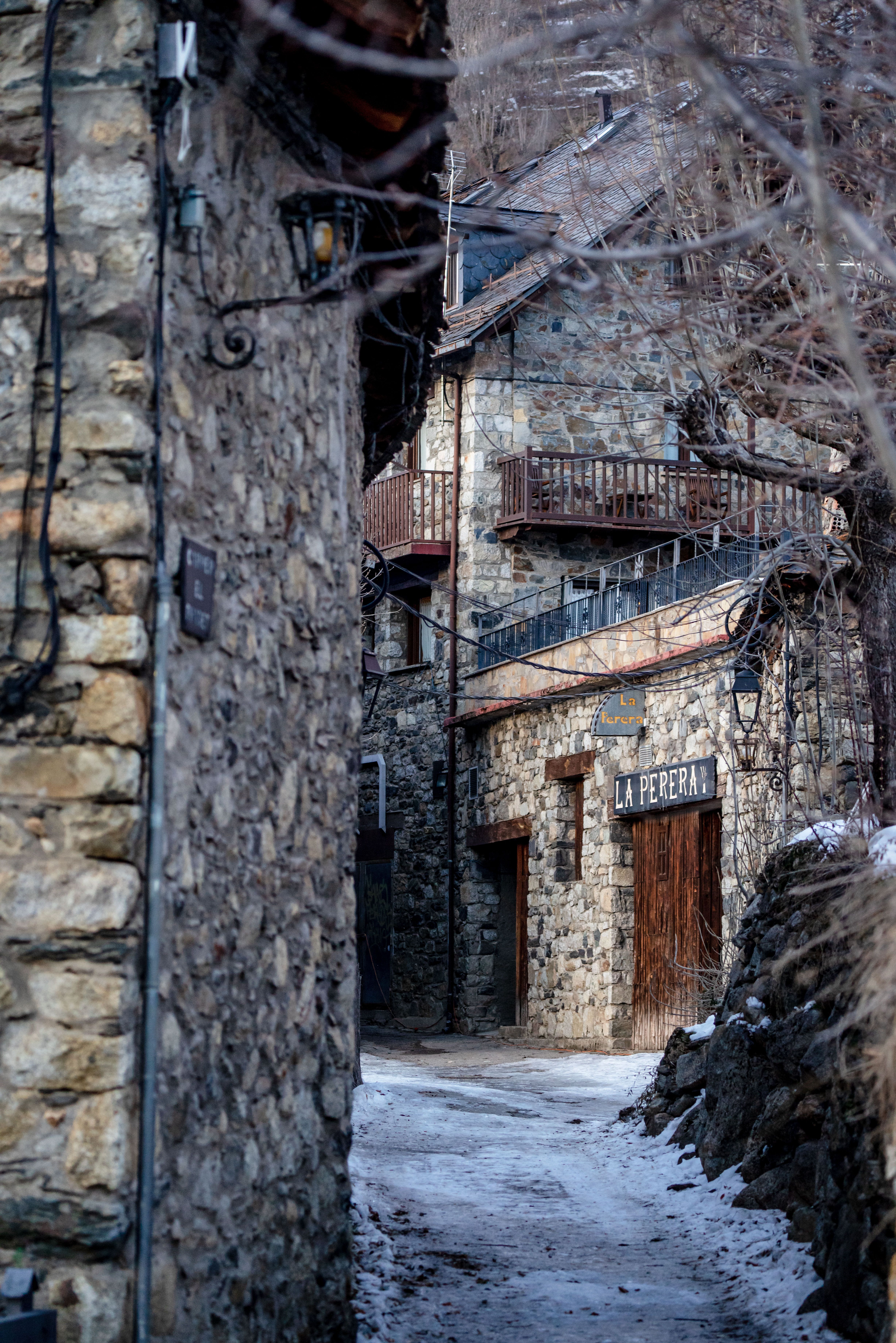 Snowy stone village street with rustic buildings in a serene winter setting.