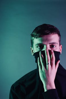 一张戏剧性的工作室肖像中，一名男子半掩着脸，散发出神秘的氛围