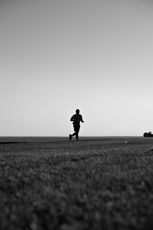 Silhouette of a Person Running on the Field