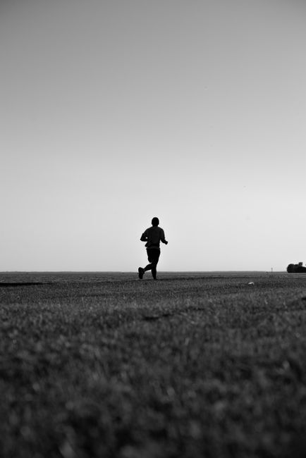 Monochrome silhouette of a person running on an open field, conveying freedom and fitness.