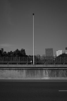 Moody black and white urban scene featuring a road, skyscrapers, and a lone streetlight.