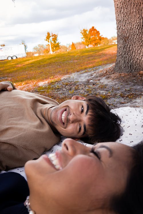 Young Couple Lying on a Blanket in a Park and Smiling 