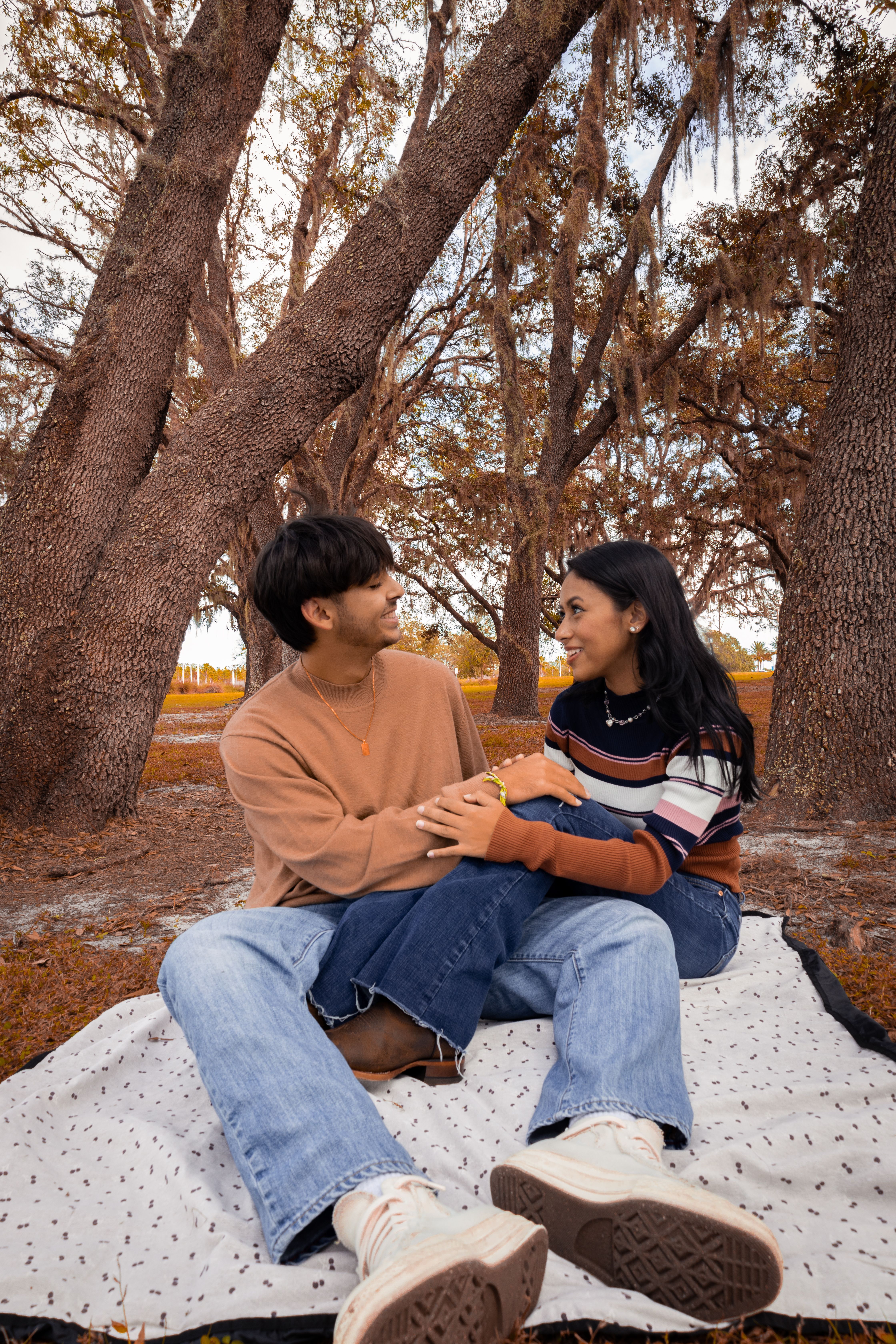 couple-sitting-on-polka-dot-picnic-blanket-beside-brown-trees-free