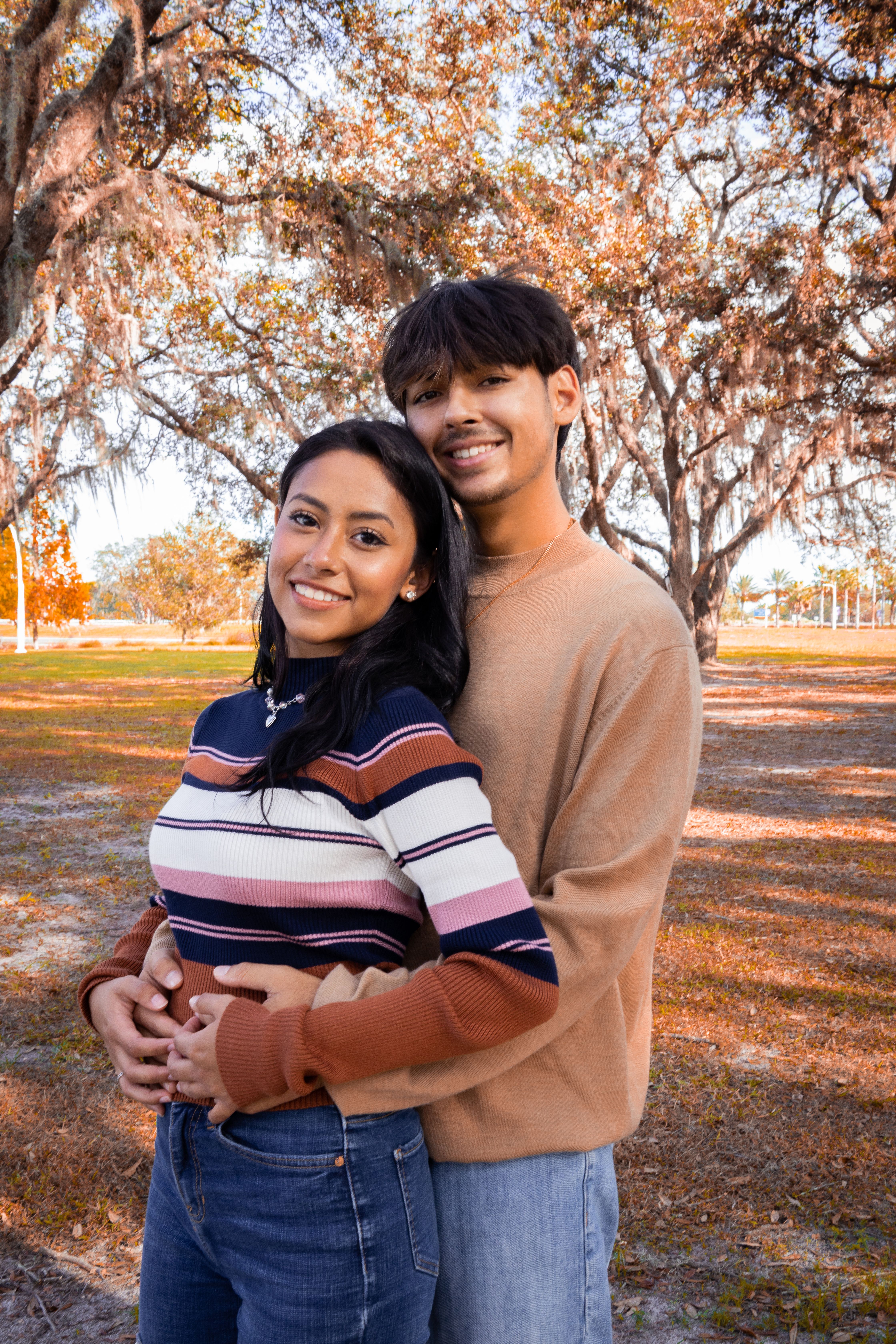 Young Couple Standing in a Park, Hugging and Smiling · Free Stock Photo