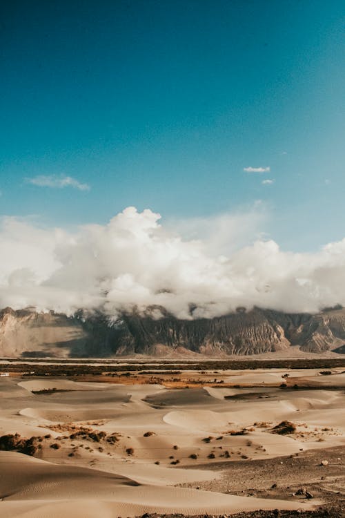 бесплатная Гора, покрытая облаками на пустынной земле Стоковое фото