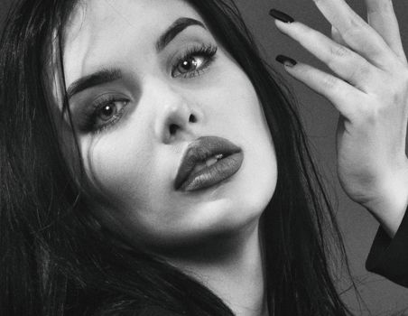 Close-up black and white portrait of a woman with expressive eyes and dark manicure.