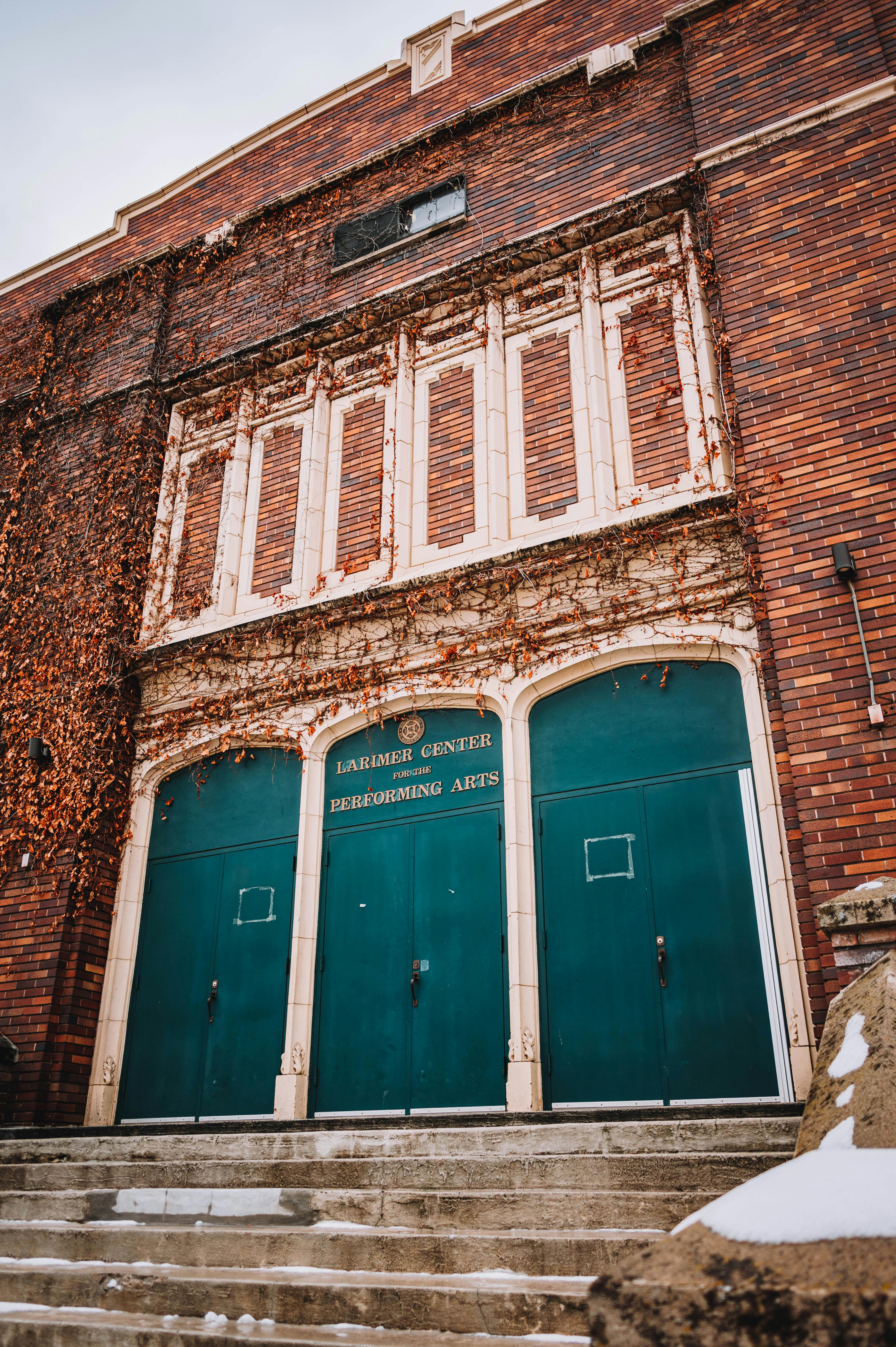 Free A vintage-style theater entrance with green doors and brick facade at the Performing Arts Center. Stock Photo