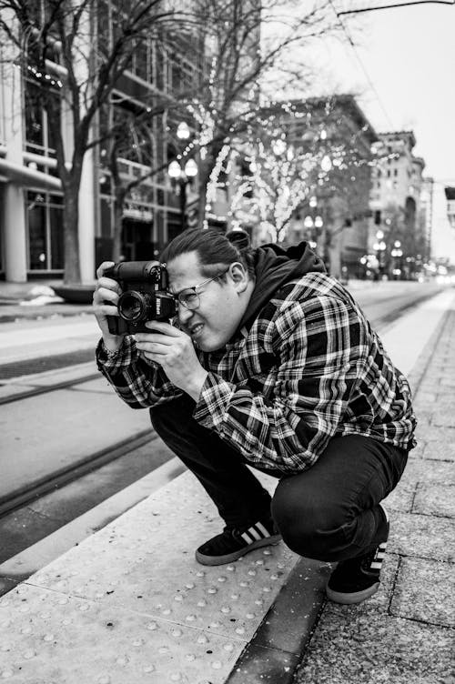 Foto profissional grátis de agachado, câmera, cidade