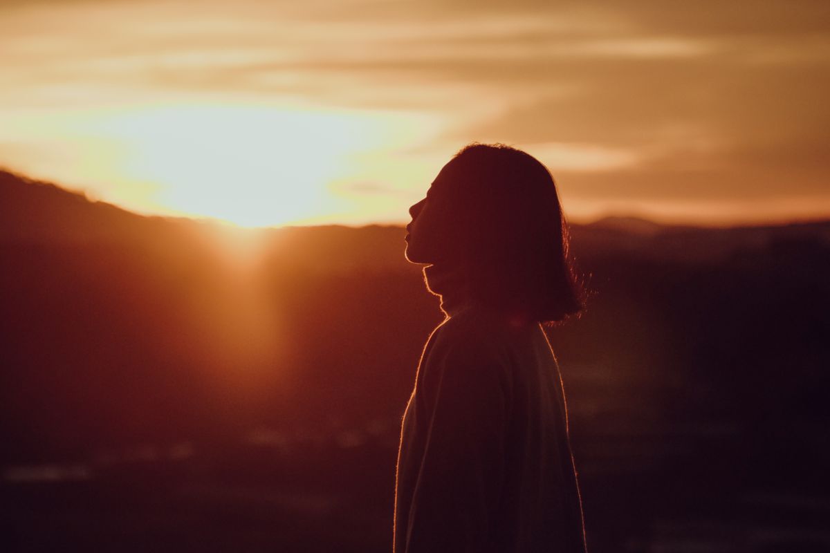 Siluet perempuan saat golden hour dengan cahaya hangat keemasan ideal untuk shooting cinematic outdoor