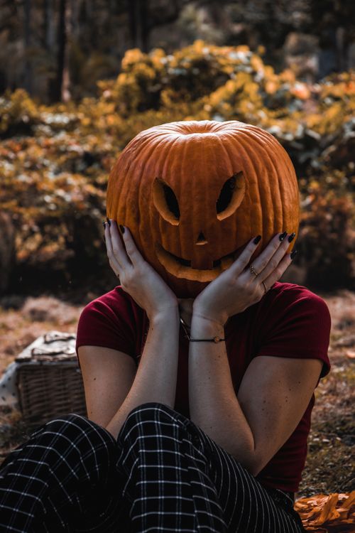 Free Person having fun with a carved pumpkin in a fall forest setting. Stock Photo
