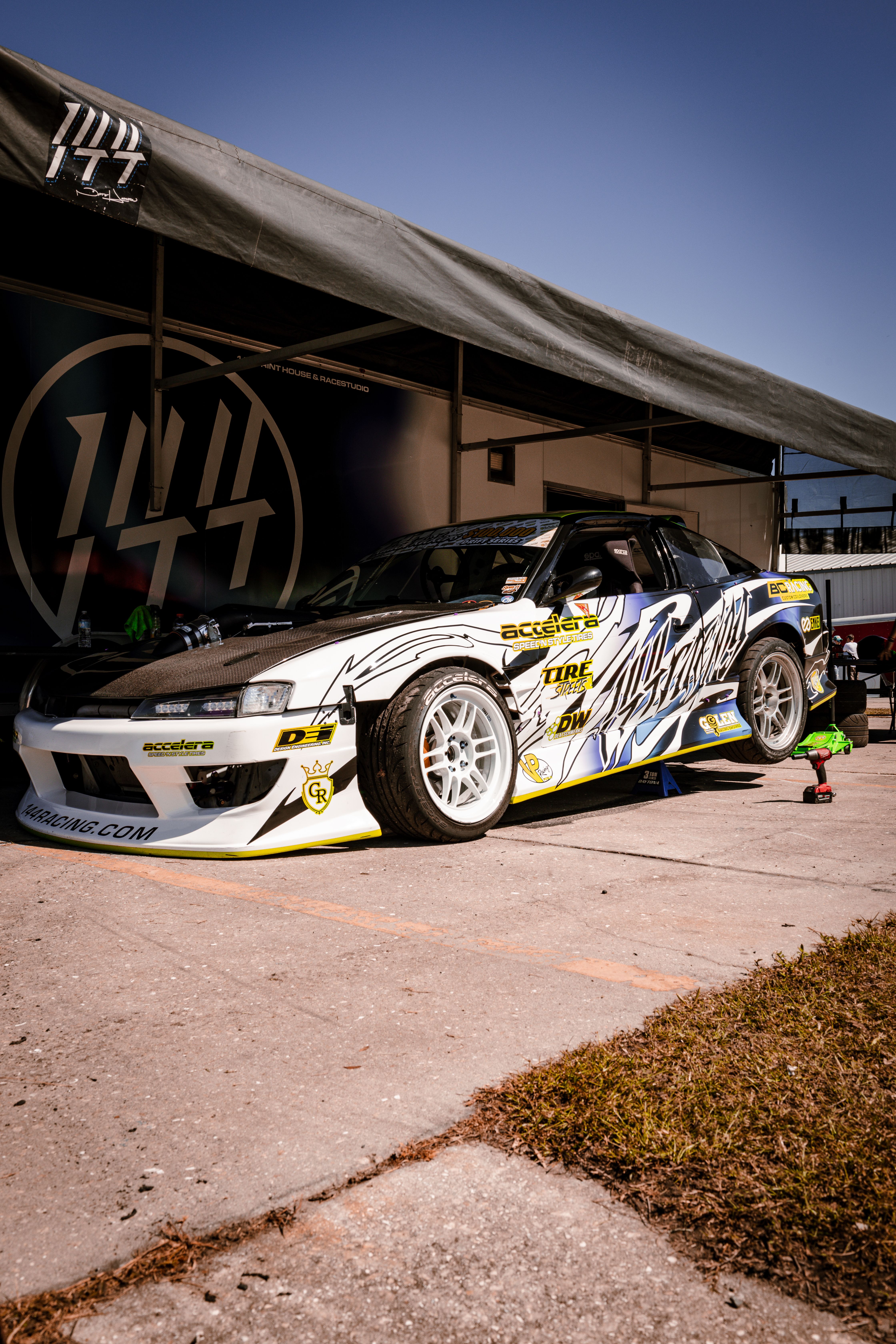 Custom racing car displayed at an outdoor motorsport event, showcasing bold graphics and design.