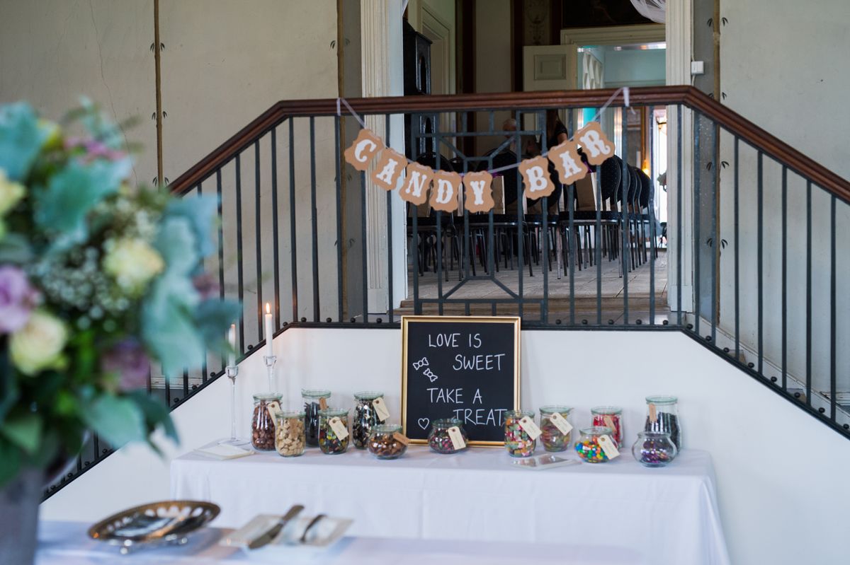 Charming candy bar setup at indoor event with variety of candies in jars and inviting decor.
