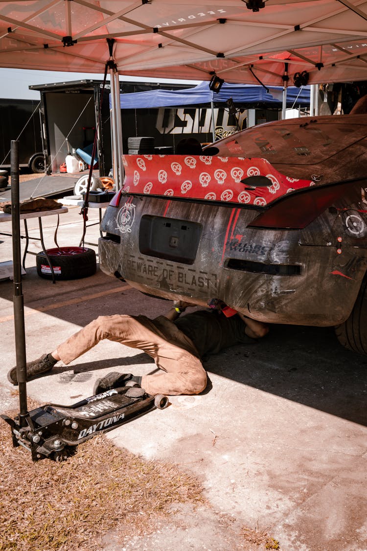 Mechanic Lying Under Raised Race Car