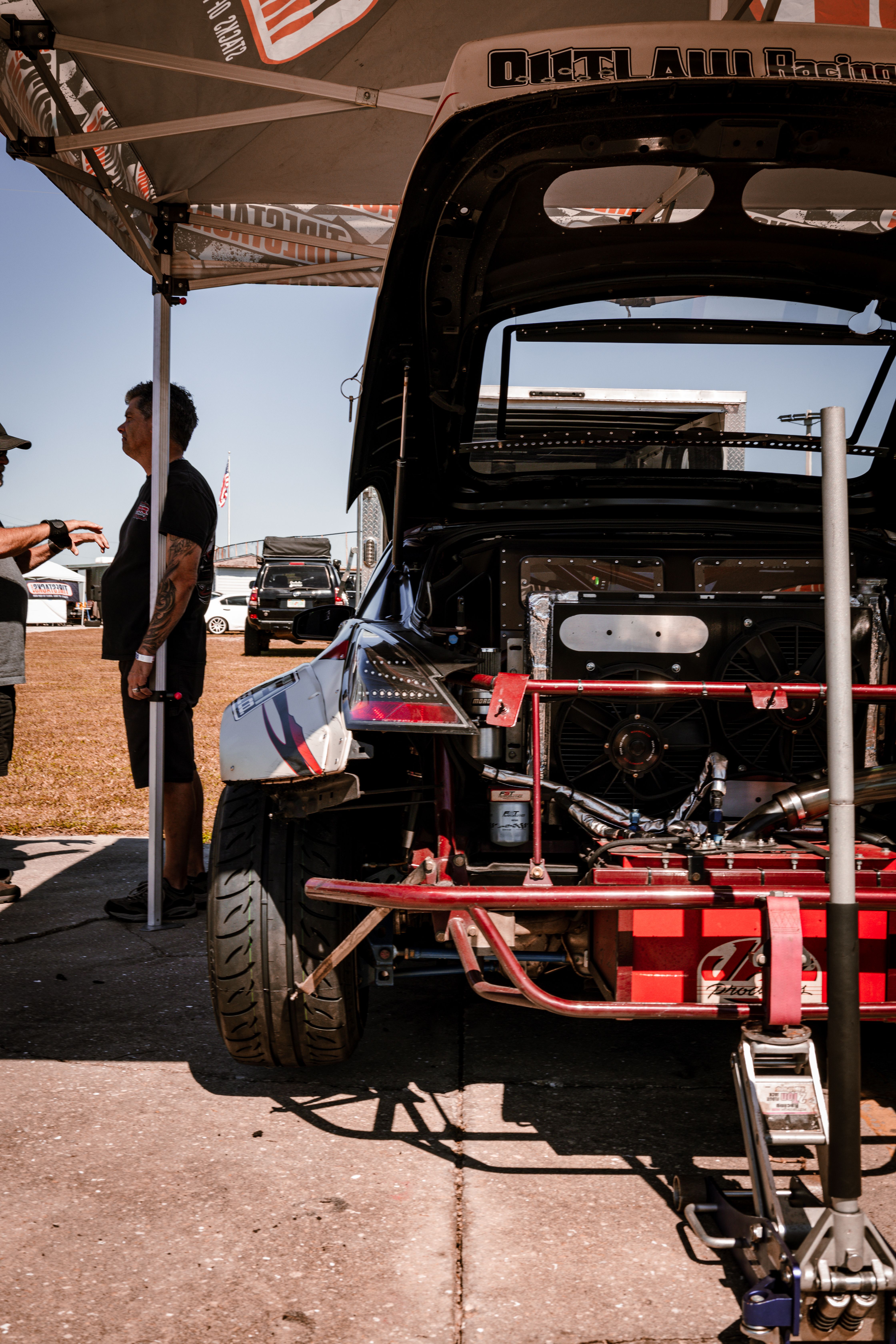 A sports car being prepared with its hood open during a race event, emphasizing speed and precision.