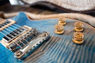 一把蓝色电吉他的详细特写，配有金色控制旋钮和金属弦