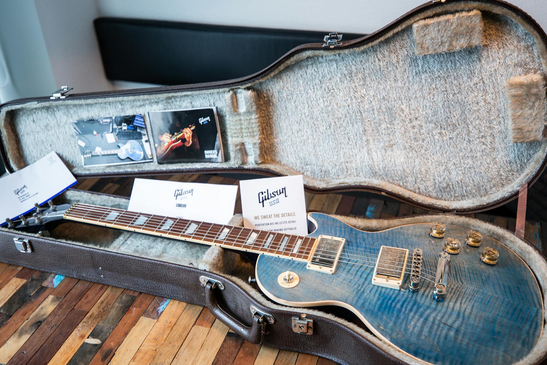 A Gibson electric guitar displayed in an open vintage case with documents.