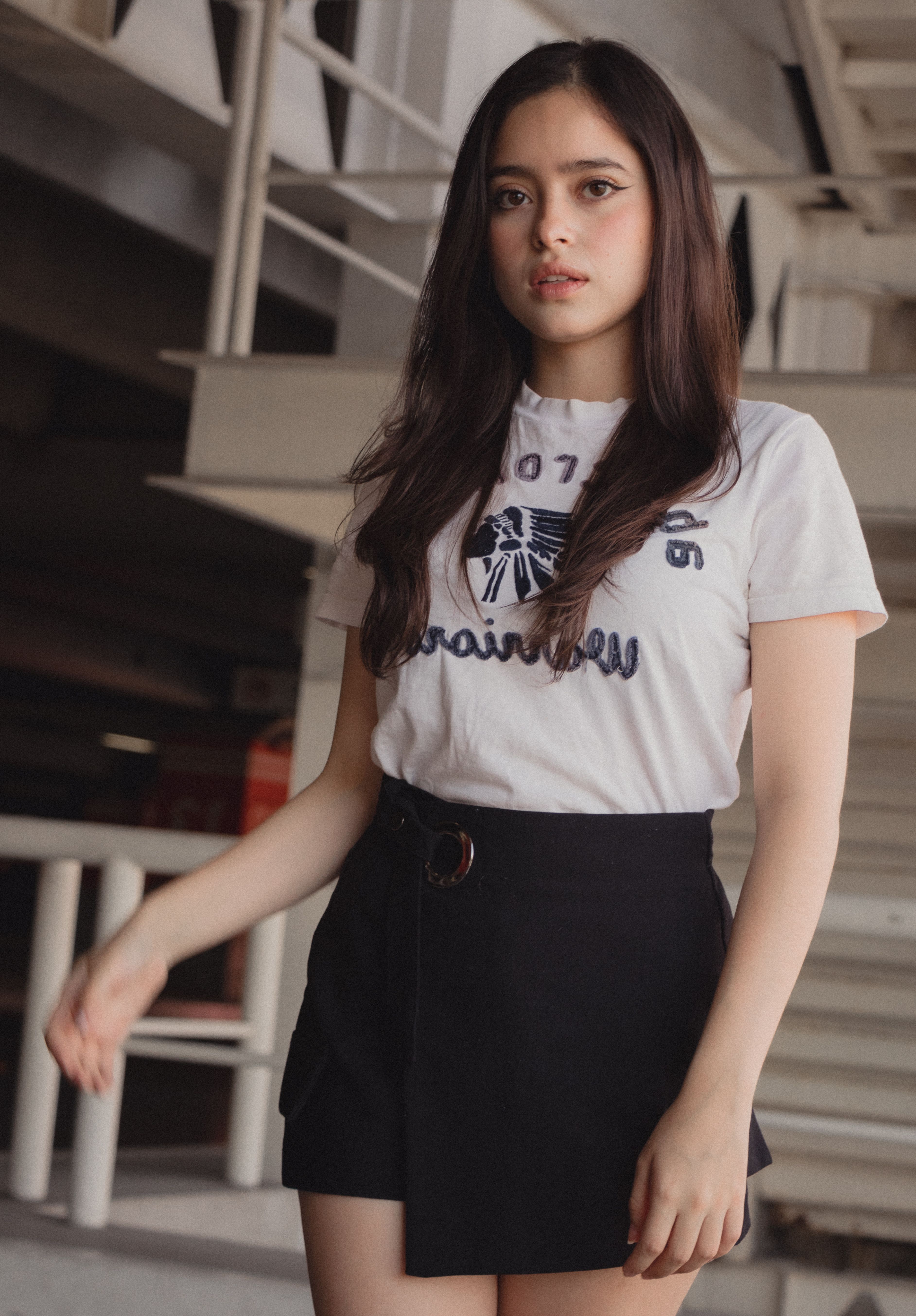 Portrait of a young woman in a chic outfit posing indoors with natural lighting.
