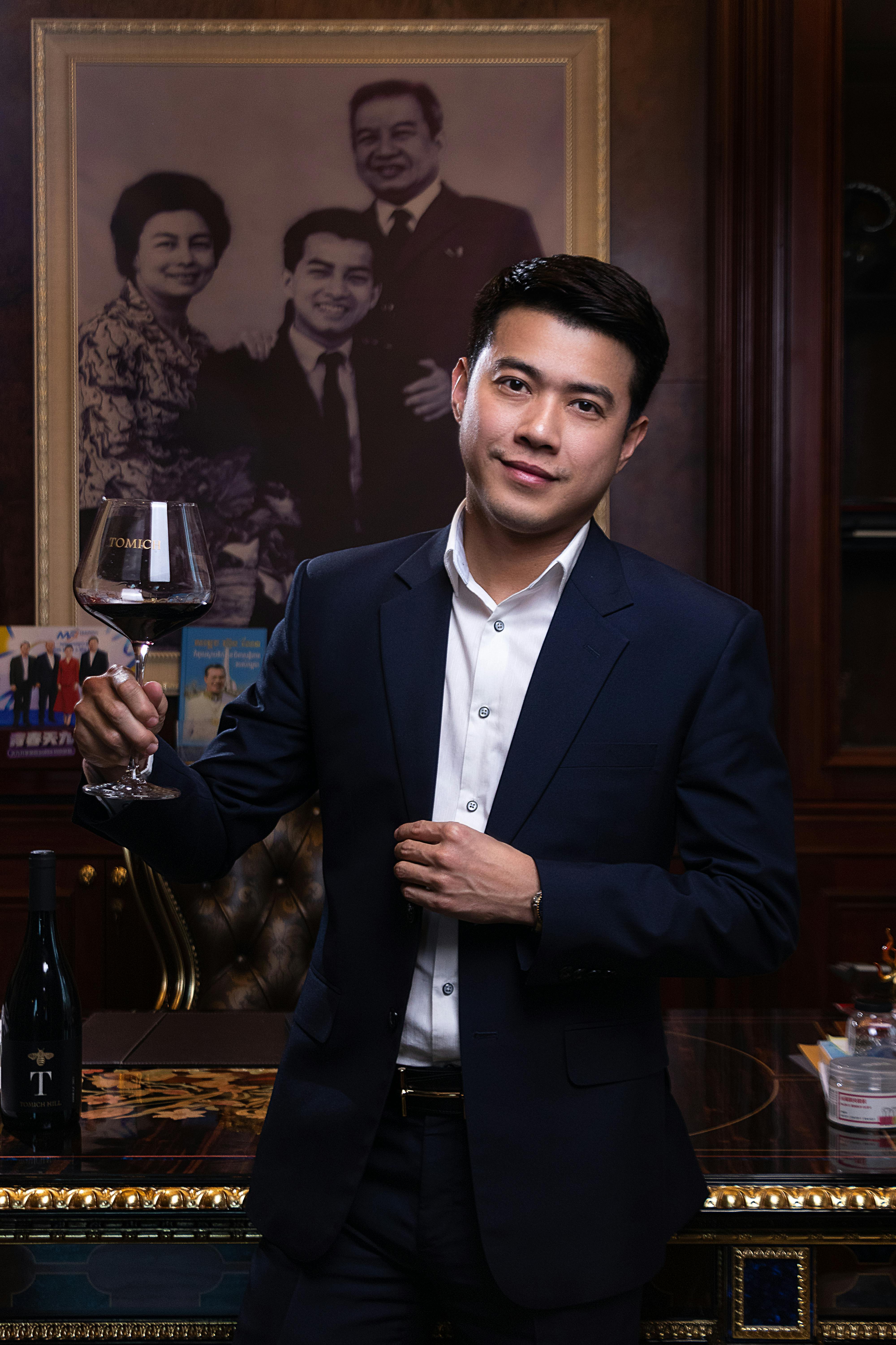 Asian businessman in suit holding a wine glass in an elegant setting.