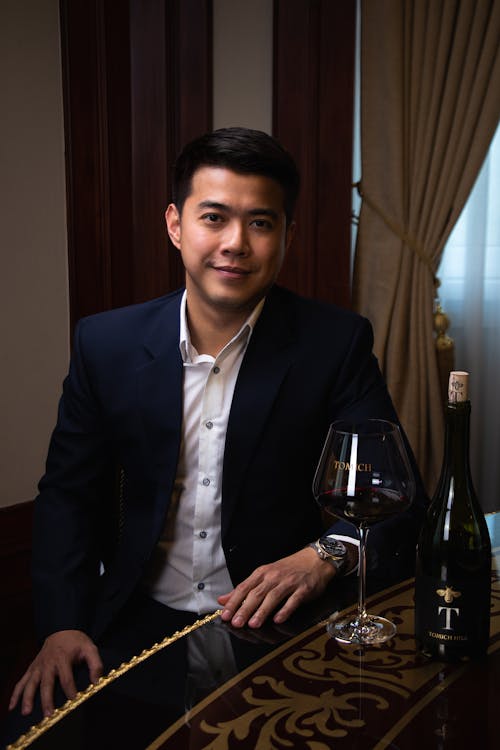 Smiling Man in Suit Sitting by Table with Wine Glass